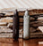 Two Meridian branded nose and ear hair trimmers, one black and one gray, positioned upright against a background of stacked natural stone slabs.