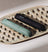 Two sleek Meridian grooming devices in black and green placed on a textured beige ceramic tray.