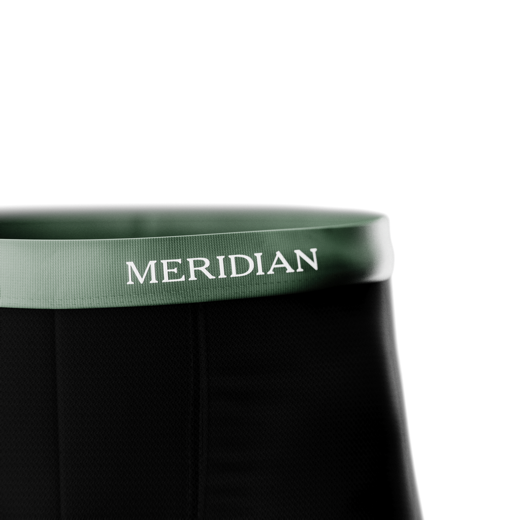 Close-up of black fabric with a green waistband featuring the "MERIDIAN" brand name in white letters.