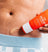Exfoliating body scrub cream being applied on abdomen, skincare product for smooth, healthy skin, men's grooming routine.